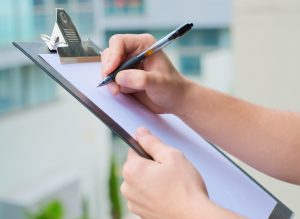 person writing on clipboard