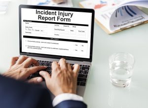 man filling out incident injury report form on laptop